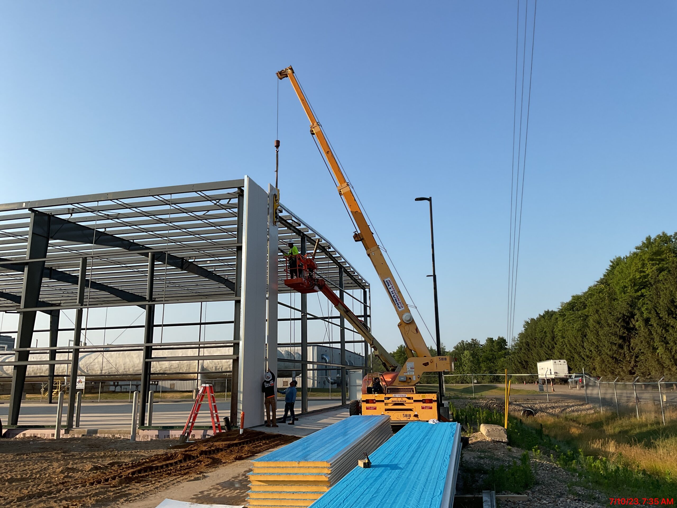 Concrete crew setting metal siding on building frame